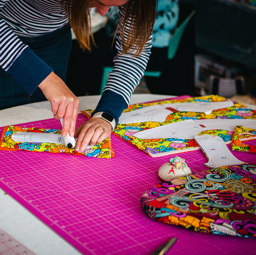 Person working on a craft project with colorful materials on a table.